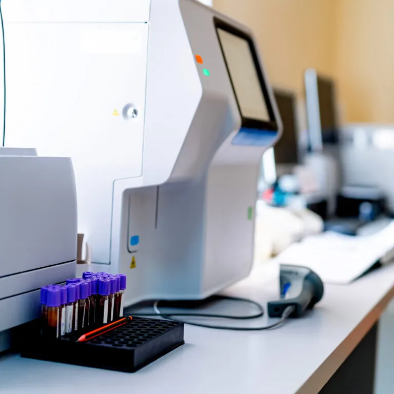 A laboratory analyzer with sample tubes on a bench
